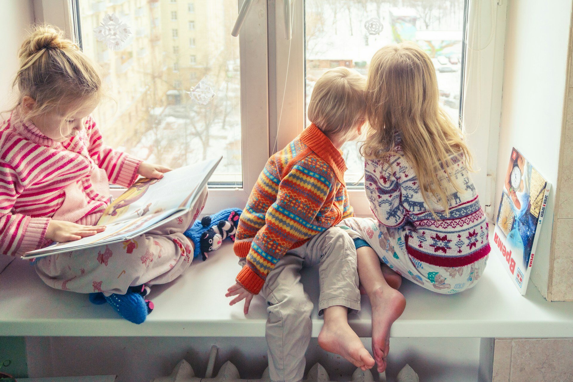 Des enfants lisant des livres assis près d'une fenêtre